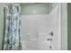 Close up of the full tub and shower with bright white tile and rainfall shower head at 9983 Cluny Ave, Las Vegas, NV 89178