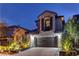 Charming home exterior at dusk featuring stone accents, a two-car garage, and manicured landscaping at 11221 Stanwick Ave, Las Vegas, NV 89138