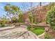 Serene backyard with a fountain, mature trees, lush landscaping, and a brick-paved patio at 2413 Hamonah Dr, Henderson, NV 89044
