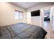 Bedroom with a gray comforter, flat screen TV and wood-look flooring, with window and door at 5250 S Rainbow Blvd # 2033, Las Vegas, NV 89118