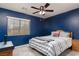 Cozy bedroom featuring a ceiling fan, natural light, a comfortable bed, and blue accent wall at 5609 Hannah Gordon Ct, North Las Vegas, NV 89081