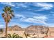 Backyard view featuring a palm tree, desert mountains, and the rooftops of a residential area at 5751 E Owens Ave, Las Vegas, NV 89110
