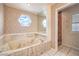Bathroom featuring a large tub with jets and a unique window at 5751 E Owens Ave, Las Vegas, NV 89110