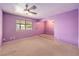 This is a bedroom with purple walls, a ceiling fan, and a window with neighborhood views at 5751 E Owens Ave, Las Vegas, NV 89110