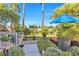 Secluded backyard with lush landscaping, cozy seating, and a blue umbrella at 8620 Cremona Dr, Las Vegas, NV 89117