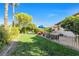 Landscaped backyard with lush green lawn and mature trees under a sunny blue sky at 8620 Cremona Dr, Las Vegas, NV 89117