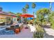 Spacious outdoor patio with comfortable seating, umbrellas, lush landscaping, and access to the home at 8620 Cremona Dr, Las Vegas, NV 89117