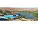 Beautiful community pool area with blue umbrellas, a lake, and a manicured golf course against a desert landscape at 950 Overland Trl, Mesquite, NV 89034