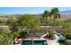 Overhead capture of a pool with stone fountain features, mature trees, and a view of the distant mountains at 950 Overland Trl, Mesquite, NV 89034