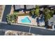 An aerial view of a uniquely shaped pool, with sun-drenched concrete decking, landscaping and neighboring rooftops at 10216 Via Roma Pl, Las Vegas, NV 89144