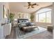 Bright, staged bedroom with a ceiling fan, artwork and a large window letting in natural light at 10216 Via Roma Pl, Las Vegas, NV 89144