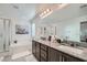 Bright bathroom with dual sinks, dark wood cabinets, granite countertops, soaking tub, and glass shower at 1328 Graphite Ave, Henderson, NV 89002