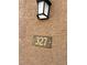 Close-up of the unit number plaque, labeled 327, affixed to a textured tan wall with a porch light above at 2900 Sunridge Heights Pkwy # 327, Henderson, NV 89052