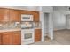 Efficient kitchen boasting wood cabinets, white appliances, tile backsplash, and an adjacent pantry for storage at 5292 Cholla Cactus Ave, Las Vegas, NV 89141