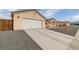 Long driveway leading to a two-car garage of a neutral home, complemented by rock landscaping at 672 Lampshire Ln, Pahrump, NV 89060