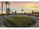 Expansive community greenspace with manicured lawns, mature trees, and desert landscaping at sunset at 872 Timber Walk Dr, Henderson, NV 89052