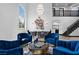 Bright living room features high ceilings, staircase, modern lighting and comfortable blue velvet seating area with a chess table at 9417 Churchill Downs Dr, Las Vegas, NV 89117