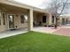 Well-maintained backyard with covered patio, artificial grass, hardscape, and mature trees offering shade at 1654 Danbury Crossing Dr, Henderson, NV 89052