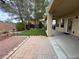 Spacious backyard featuring a covered patio, brick pavers, well-kept artificial grass, and mature trees at 1654 Danbury Crossing Dr, Henderson, NV 89052