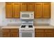 Kitchen with wood cabinets, white appliances, and a white countertop with an oven and microwave at 1654 Danbury Crossing Dr, Henderson, NV 89052