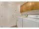 Convenient laundry area with washer, dryer, and overhead cabinets near a door to the outside at 178 Beach Oak Ave, Henderson, NV 89002