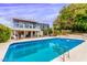 A large pool and blue two-story home with deck, a covered patio, and a lush backyard in a residential setting at 2058 Ottawa Dr, Las Vegas, NV 89169