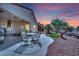 Well-maintained backyard with a covered patio, outdoor seating, desert landscaping and picturesque sunset at 2077 Wildwood Lake St, Henderson, NV 89052