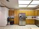 Well-lit kitchen showcasing wooden cabinets, stainless steel refrigerator, tile flooring and modern lighting at 2270 Canyon Song Ave, Laughlin, NV 89029