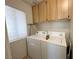Laundry room showcasing a white washer and dryer set beneath a window and upper cabinets at 2270 Canyon Song Ave, Laughlin, NV 89029