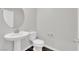 Small powder room with pedestal sink, toilet, and round mirror at 2449 Padulle Pl, Henderson, NV 89044