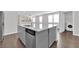 Modern kitchen island featuring gray cabinets, stainless steel appliances, and adjacent laundry space at 2449 Padulle Pl, Henderson, NV 89044