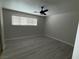 Bedroom featuring light gray walls, ceiling fan, wide window and gray wood floors at 325 Greenfield Ln, Las Vegas, NV 89107