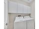 Bright laundry room featuring white front-loading washer and dryer with storage cabinets above for organization at 4224 Galapagos Ave, North Las Vegas, NV 89084