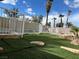 Backyard with synthetic grass, stone details, mature landscaping, and a secure white fence surrounding the pool area at 4417 De Forest St, Las Vegas, NV 89103