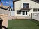 Landscaped backyard with artificial turf, a brick-lined fire pit, and an upper-level balcony at 4417 De Forest St, Las Vegas, NV 89103