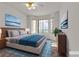 Cozy staged primary bedroom featuring a bed, bay windows, night stands, and a ceiling fan at 5401 Tassara Way # 102, Las Vegas, NV 89108