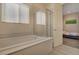 Bright bathroom features a soaking tub under a window and a glass-enclosed shower adjacent to an open doorway at 5518 Taylor Rose Ave, Las Vegas, NV 89139