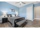 Contemporary bedroom with a sleek black bed, hardwood floors, and a soothing blue accent wall at 5523 Taylor Rose Ave, Las Vegas, NV 89139