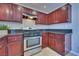 Galley kitchen featuring cherry cabinets, stainless steel appliances, and tile flooring at 5854 Heather Marie Dr, Las Vegas, NV 89110