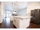 Spacious kitchen with white cabinets, large center island, stainless steel fridge and dark wood flooring at 6440 N Bruce St, North Las Vegas, NV 89086