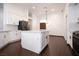 Bright kitchen features an island with white cabinets, stainless steel appliances, and dark wood-look flooring at 6440 N Bruce St, North Las Vegas, NV 89086