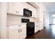 Kitchen with white cabinets, black appliances and dark wood flooring at 6440 N Bruce St, North Las Vegas, NV 89086