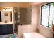 Bright bathroom featuring a glass shower, tub, stained glass window, and sleek vanity at 9113 Anchor Cove Ct, Las Vegas, NV 89117