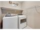 A well-lit laundry room with a washer, dryer, shelving and laundry-themed wall decor at 1427 Brushback Ave, Henderson, NV 89074