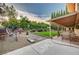 Picturesque backyard featuring a covered patio, manicured lawn, lush garden beds, and mature trees at 1546 Georgia Ave, Boulder City, NV 89005