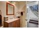 Powder room with a dark wood vanity, decorative mirror, and convenient access to the staircase at 1546 Georgia Ave, Boulder City, NV 89005