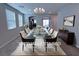 Elegant dining room featuring a chandelier, large windows, and a modern glass table set for eight at 22 Kaku Ridge Way, Las Vegas, NV 89183