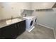 Bright laundry room features granite counters, basin sink, tile floor and modern white front load washer and dryer at 22 Kaku Ridge Way, Las Vegas, NV 89183