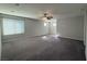 Spacious living room with neutral walls, gray carpet, ceiling fan and natural light from multiple windows at 22 Kaku Ridge Way, Las Vegas, NV 89183