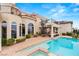 Inviting backyard featuring a sparkling pool, spa, brick patio, lush landscaping, and an outdoor living area at 2660 Mirabella St, Henderson, NV 89052